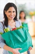 Woman holding bag of fresh vegetables.