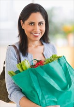 Woman holding bag of fresh vegetables.