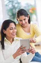 Mother and daughter (12-13) using digital tablet.