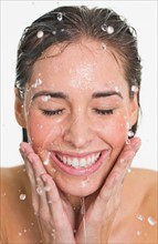 Studio shot of woman with splash of water on face.