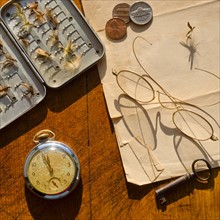 Studio shot of old pocket watch glasses, coins and fake flies.