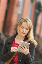 Woman using digital tablet on street.