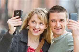 Couple photographing themselves with smart phones.