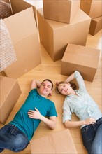 Couple lying among cardboard boxes during relocation.