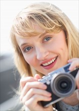 Portrait of smiling woman with camera.