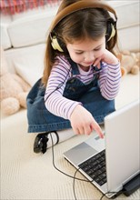 Small girl  (4-5 years) listening to music from laptop. Photo : Jamie Grill