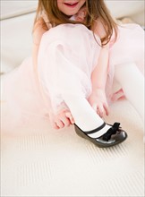 Small girl  (4-5 years)  in tulle dress putting on shoe. Photo : Jamie Grill