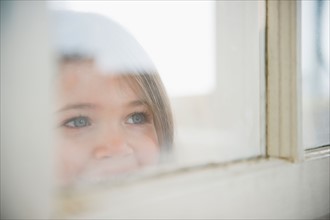 Small girl  (4-5 years) looking through window. Photo : Jamie Grill
