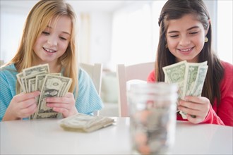 Two girls counting banknotes. Photo : Jamie Grill