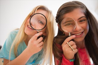 Two girls looking through magnifying glasses. Photo : Jamie Grill