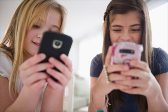 Two girls texting on smart phones. Photo : Jamie Grill
