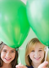 Two girls holding green balloons. Photo : Jamie Grill