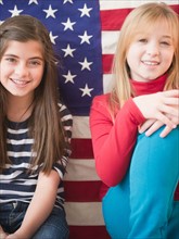 Portrait up of two girls in front of american flag. Photo : Jamie Grill