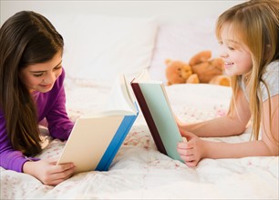 Two girls reading in bed. Photo : Jamie Grill