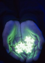 Close up of hands holding  fluorescent stars , studio shot. Photo : Jamie Grill