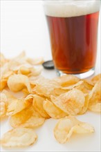 Close up of potato chips and glass of beer, studio shot. Photo : Jamie Grill