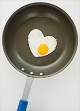 Close up of fried egg in heart shape on frying pan, studio shot. Photo : Jamie Grill