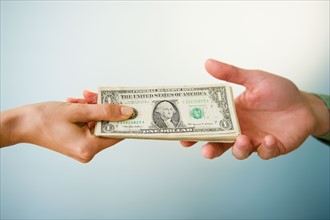 Close up of man's and woman's hands holding banknotes, studio shot. Photo : Jamie Grill