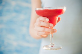 Close up of woman's hand holding cocktail, studio shot. Photo : Jamie Grill