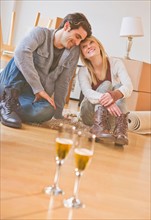 Close up of wine glasses on floor with couple behind. Photo : Daniel Grill