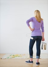 Rear view of woman holding paint can and paint roller. Photo : Daniel Grill