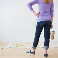 Rear view of woman holding paint can and paint roller. Photo : Daniel Grill