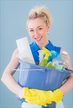 Portrait of young woman carrying cleaning equipment, studio shot. Photo : Daniel Grill