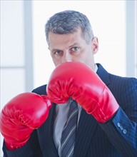Businessman wearing red boxing gloves. Photo : Daniel Grill