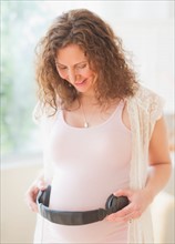 Portrait of pregnant woman holding headphones on her belly. Photo : Daniel Grill