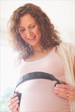 Portrait of pregnant woman holding headphones on her belly. Photo : Daniel Grill