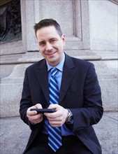 USA, New York, New York City. Portrait of businessman with smartphone. Photo : Winslow Productions