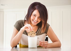 Young woman eating cookie with milk. Photo : Mike Kemp