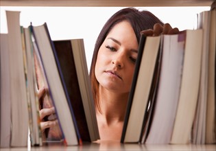 Portrait of young woman searching book on shelf. Photo : Mike Kemp
