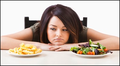 Young woman choosing between healthy and unhealthy food. Photo : Mike Kemp
