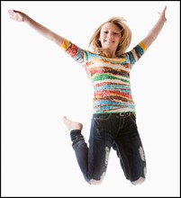 Studio shot of girl (12-13) jumping with arms raised. Photo : Mike Kemp