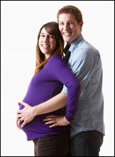Man embracing pregnant woman, studio shot. Photo : Mike Kemp