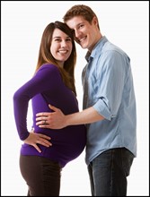 Man embracing pregnant woman, studio shot. Photo : Mike Kemp