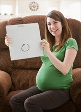 Portrait of pregnant woman showing calendar with due date. Photo : Mike Kemp
