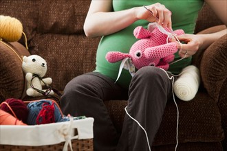 Portrait of pregnant woman preparing stuffed toys for baby. Photo : Mike Kemp