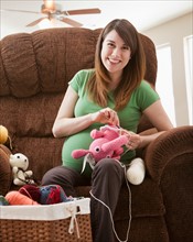 Portrait of pregnant woman preparing stuffed toys for baby. Photo : Mike Kemp