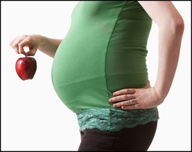 Pregnant woman holding red apple. Photo : Mike Kemp