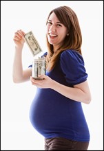 Studio Shot of woman holing baby jar with money. Photo : Mike Kemp