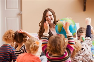 Geography teacher with children (2-3, 4-5) raising hands. Photo : Mike Kemp