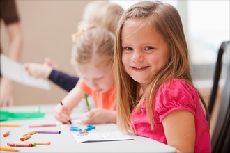 Girl (4-5)  looking at camera during art lesson in kindergarten. Photo : Mike Kemp