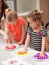 Girls (4-5) holding their hands on plates with paint. Photo : Mike Kemp
