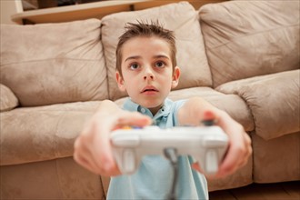Front view of boy (8-9) playing Video Games. Photo : Mike Kemp