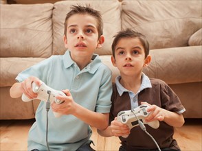 Front view of two boys (6-7, 8-9) playing Video Games. Photo : Mike Kemp