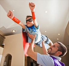 Father holding aloft his son (8-9) dressed up in fancy dress costume. Photo : Mike Kemp
