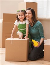 Portrait of mother with daughter (4-5) surrounded by cardboard boxes. Photo : Mike Kemp