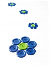 Studio shot of blue and green buttons arranged in flower head. Photo : David Arky